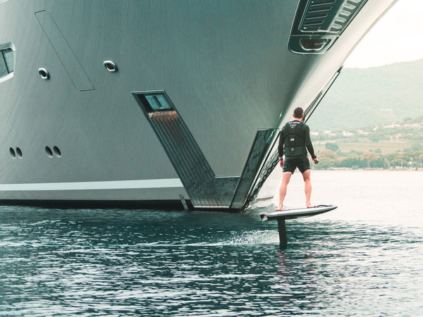 Man riding Awake VIGNA efoil in front of a yacht.
