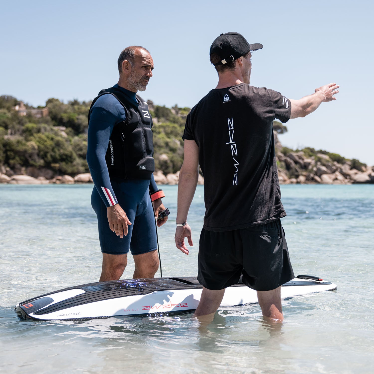 Two men standing by a Ravik 3 jet board. One man points into the distance.