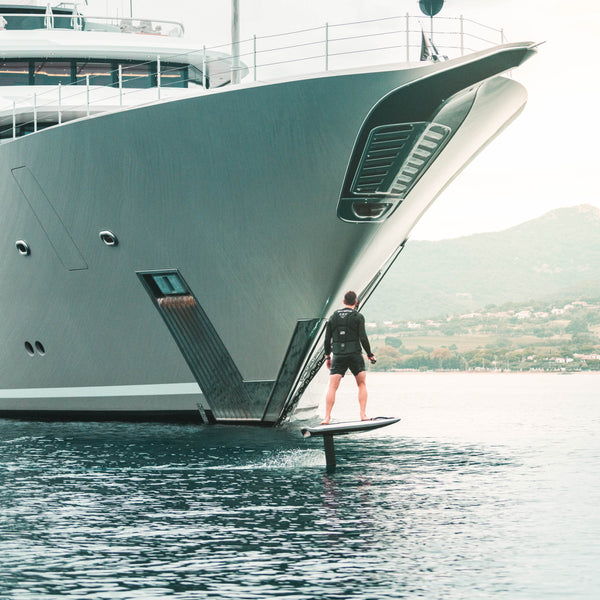 Man riding Awake VIGNA efoil in front of a yacht.
