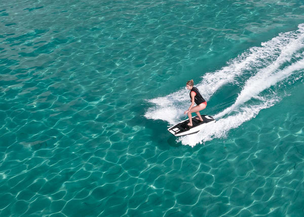 A girl effortlessly glides over a crystal clear turquoise sea on an Awake RÄVIK 3 electric jetboard.