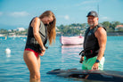 A woman zipping up an Awake Life Vest and a man wearing an Awake Life Vest and smiling.