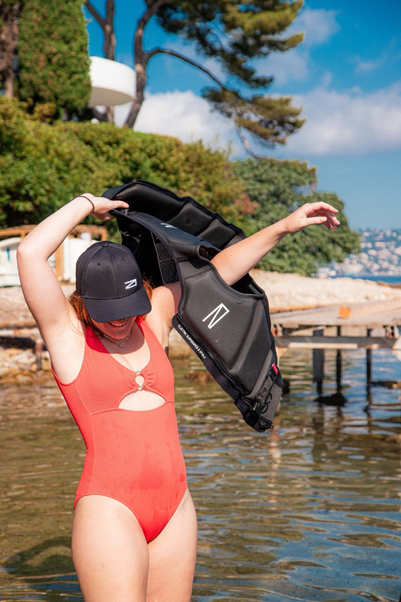 Woman in a red bathing suit putting on an Awake Life Vest 