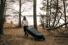 A woman carrying the RAVIK Board Bag Kits to the lake